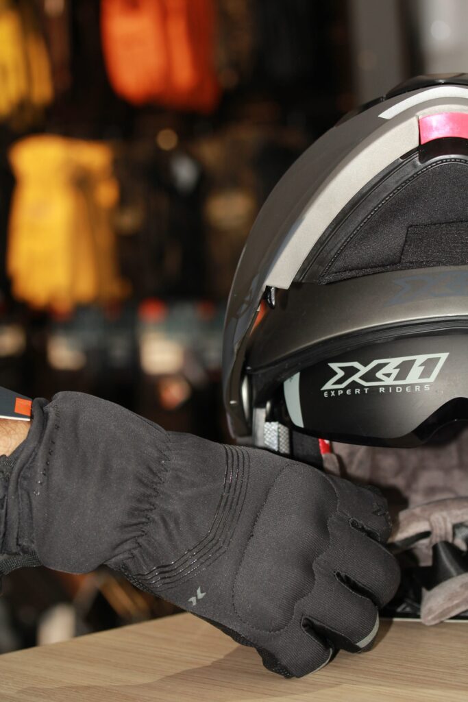 Luva preta ao lado de um capacete de motocicleta cinza