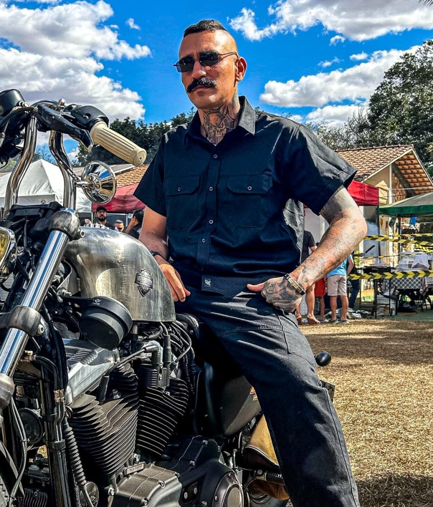 Homem estiloso com tatuagens e bigode em uma motocicleta