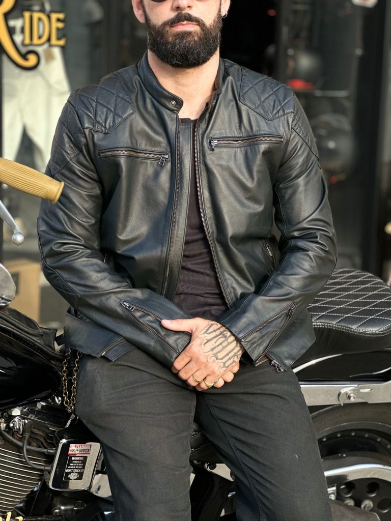 Homem barbudo em jaqueta de couro preta sentado em uma motocicleta