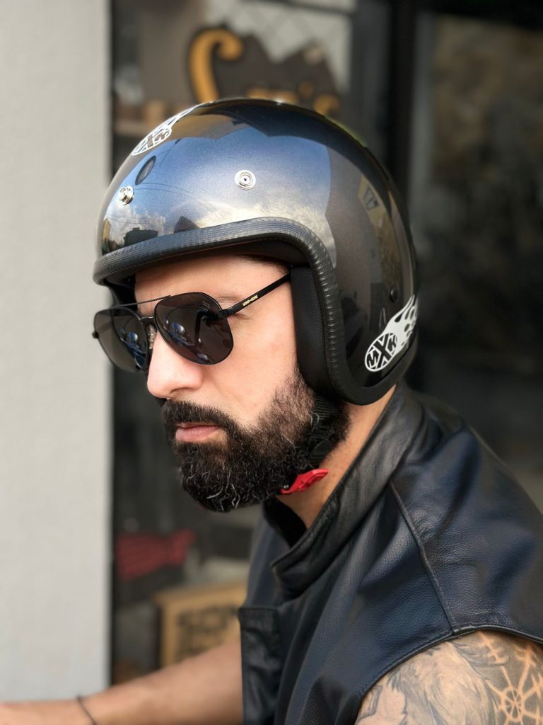 Homem barbudo de perfil usando capacete e óculos de sol