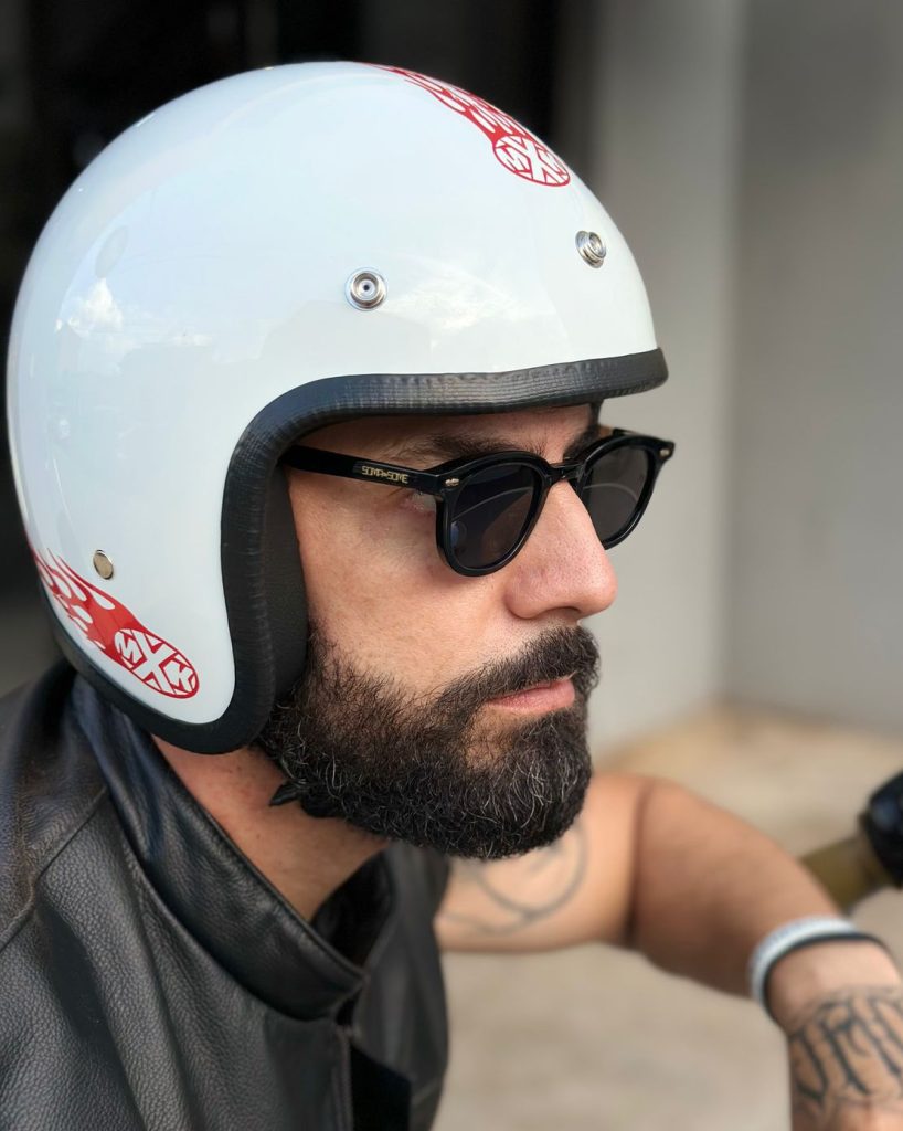 Homem barbudo de óculos de sol e capacete de motocicleta